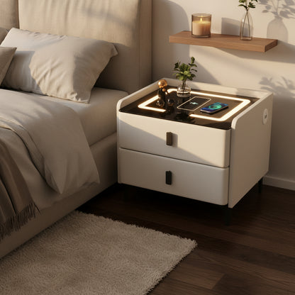A modern bedside table shown in a bedroom setting next to a bed, with dimension labels indicating 45 cm height and 40/45/50 cm width/depth options. The table has a white textured exterior, black legs, a black top surface with a built-in LED light ring, and a wireless charging pad.